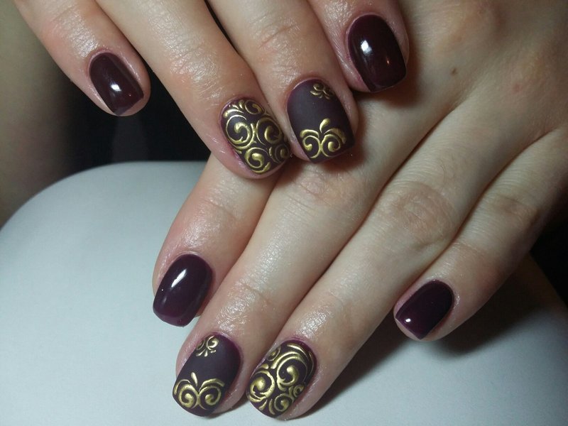 Bourgondische manicure met gouden monogrammen.