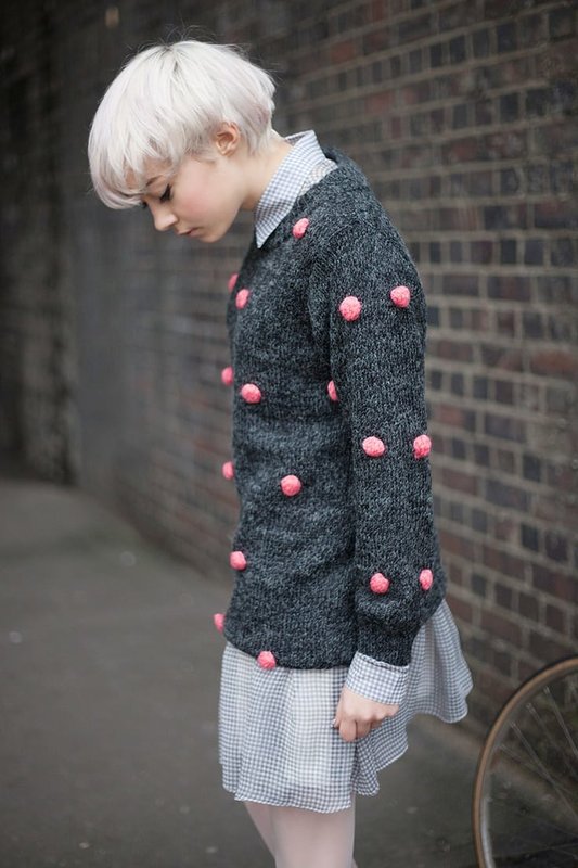 Fille en pull à pompons roses sur une robe