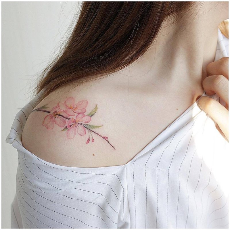 Delicate bloemtattoo op de schouder