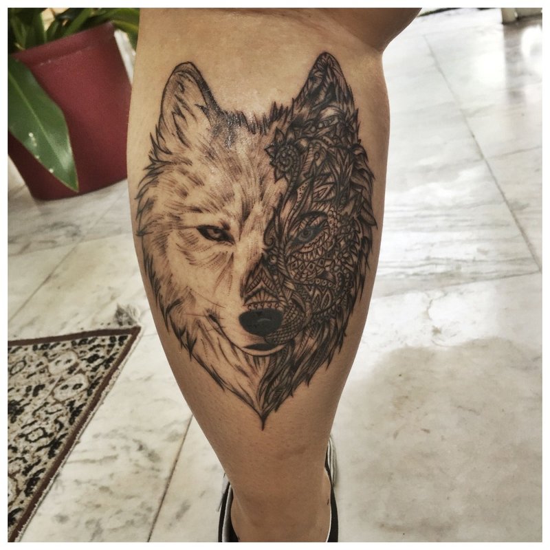 Mooie wolftattoo op het kalf van een man