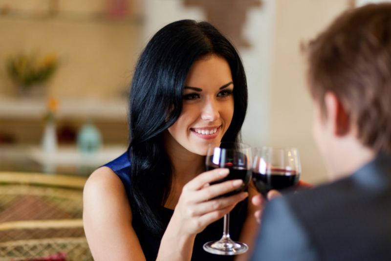 La fille avec un verre regarde le gars dans les yeux